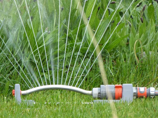 Irrigation system watering a healthy green lawn in the morning sun